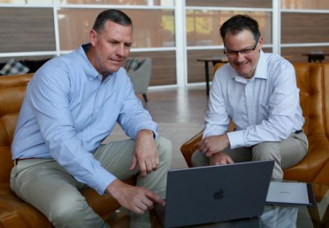 A photo of two HWAW Staff members having a discussion over a laptop